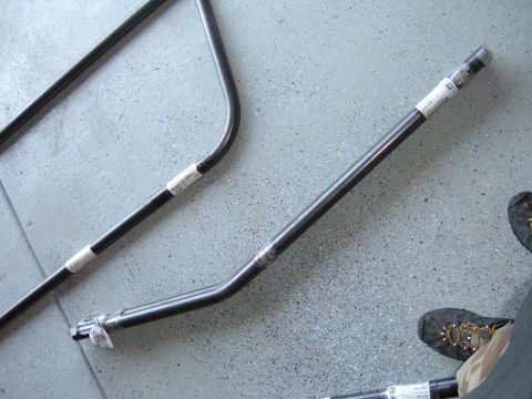 1993 Ford Bronco - Several black metal bars with white labels are laid out on a speckled gray floor.