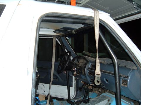 1993 Ford Bronco - The interior of a 1993 Ford Bronco shows a roll cage installed over the blue dashboard and seats.