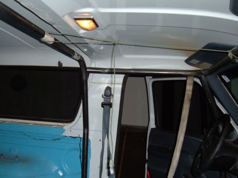 1993 Ford Bronco - The interior of a van shows a roll cage, seatbelt, and a dome light.