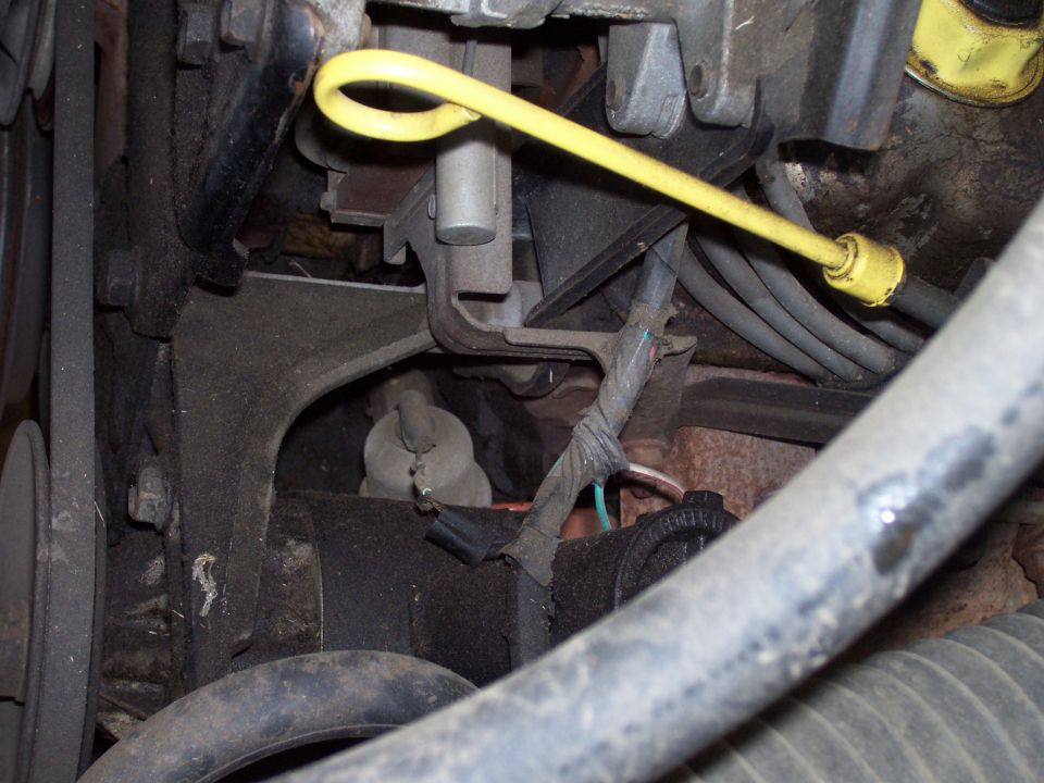 Engine bay with yellow dipstick, hoses, and belts