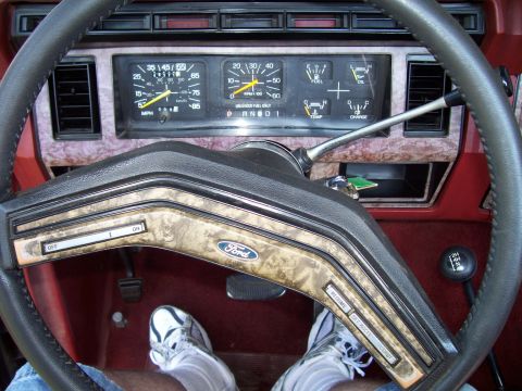 1985 Ford Bronco - The interior of a vehicle, the dashboard, steering wheel with Ford emblem, and a four-wheel drive selector.