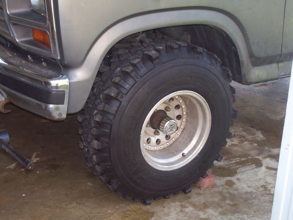 Close-up of a large off-road tire on a silver Ford truck, showing the front bumper and fender