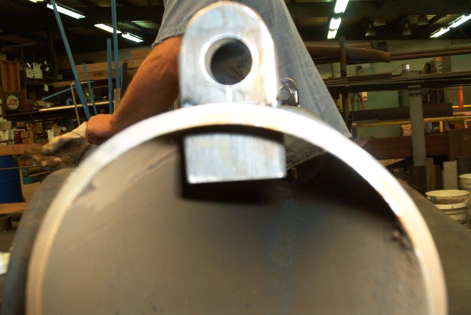 Close-up of a metal pipe with a U-shaped bracket attached, inside a workshop