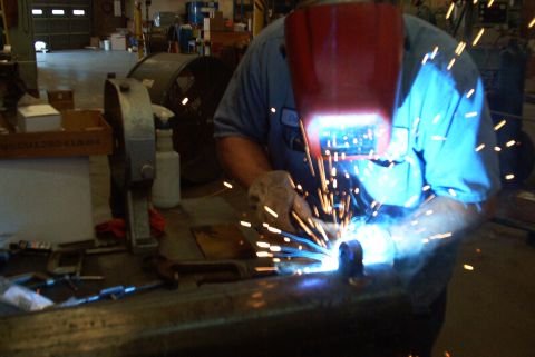 1983 Ford Bronco - A person is welding metal in a workshop, with sparks flying around them.