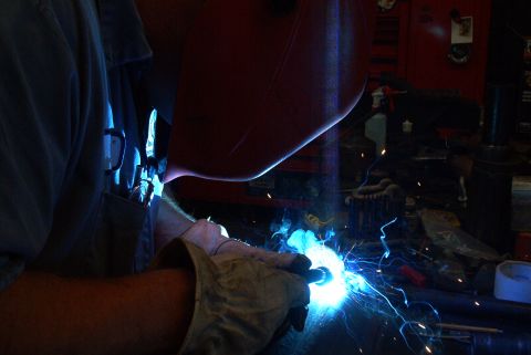 1983 Ford Bronco - A person is welding in a workshop, creating a bright blue arc and sparks.