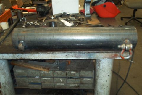 1983 Ford Bronco - Cylindrical metal part with eye bolts, likely a component for a larger assembly.
