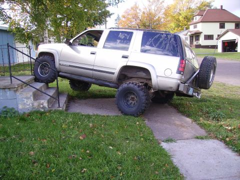 2000 Chevrolet Tahoe - This SUV is attempting to climb a set of outdoor stairs, with its front tires on the steps and rear tires on the ground.