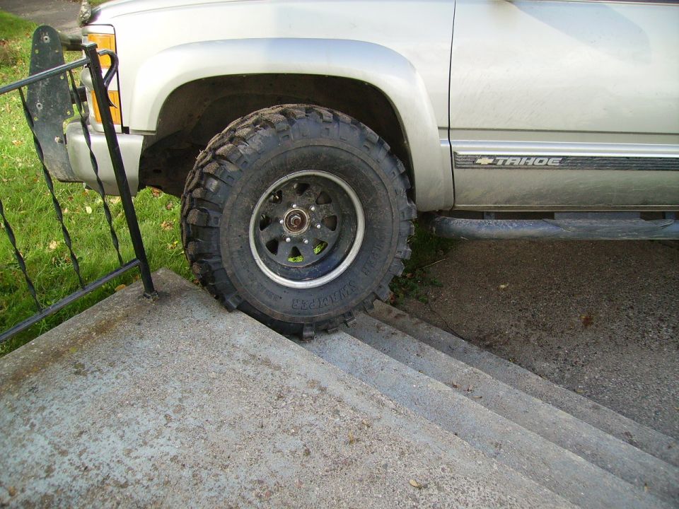 Silver 2000 Chevrolet Tahoe side view with large off-road tires on stairs