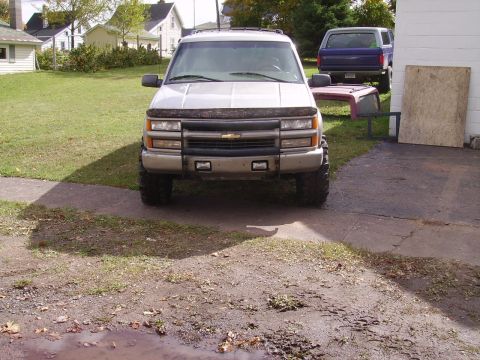 2000 Chevrolet Tahoe - A silver SUV is parked in a driveway with a blue SUV in the background.