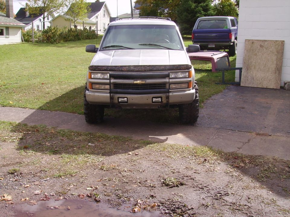 Silver SUV with aftermarket grille and large tires parked in a driveway