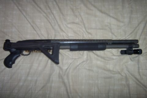 1998 Ford Crown Victoria - A shotgun with a pistol grip and tactical stock is laid out on a textured surface.