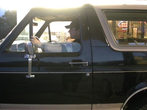 1988 Ford Bronco - A driver is visible behind the wheel of this 1988 Ford Bronco, seen from the side.