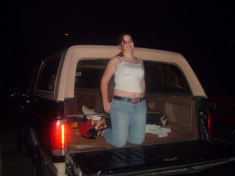 1988 Ford Bronco - A woman poses in the cargo area of a vintage SUV at night.