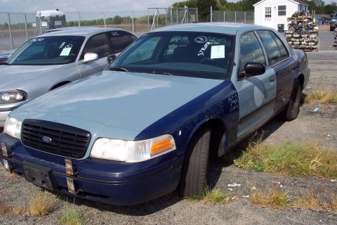 1991 Ford LTD Crown Victoria - A two-tone Ford Crown Victoria sedan sits in an outdoor lot, showing signs of wear and tear.