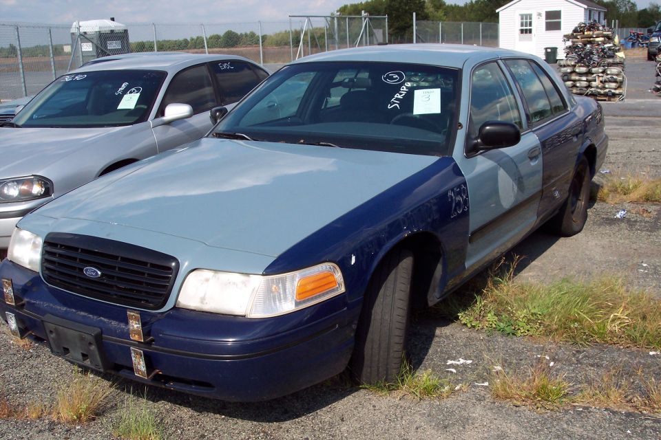 Ford Crown Victoria sedan, two-tone blue and gray, with visible damage and markings