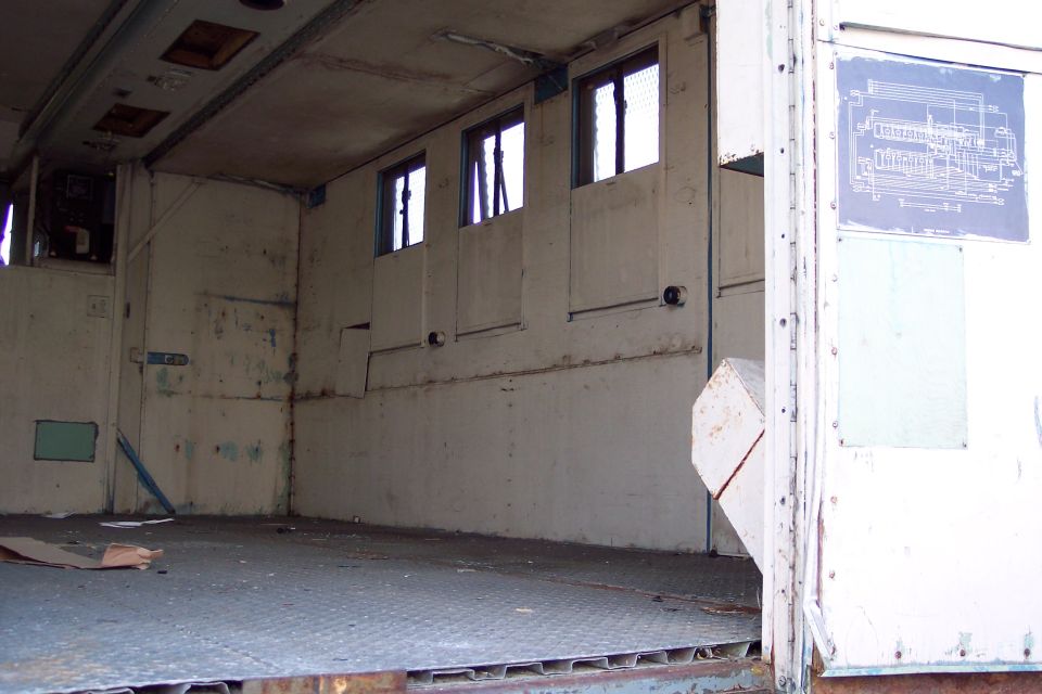 Interior of a white cargo van with diamond plate floor, three windows, and a blue diagram on the wall