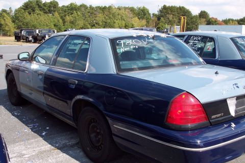 1991 Ford LTD Crown Victoria - Rear view of a two-tone police car parked in a lot with other vehicles.