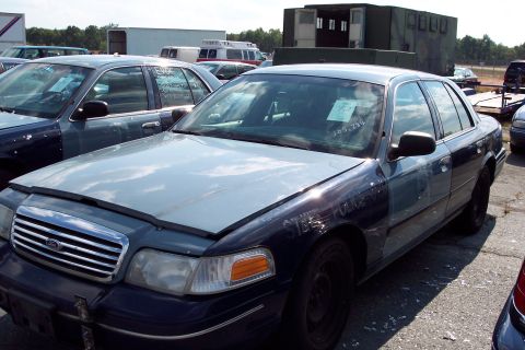 1991 Ford LTD Crown Victoria - A dark blue Ford Crown Victoria, possibly a police car, sits in a lot with its hood open and visible damage.