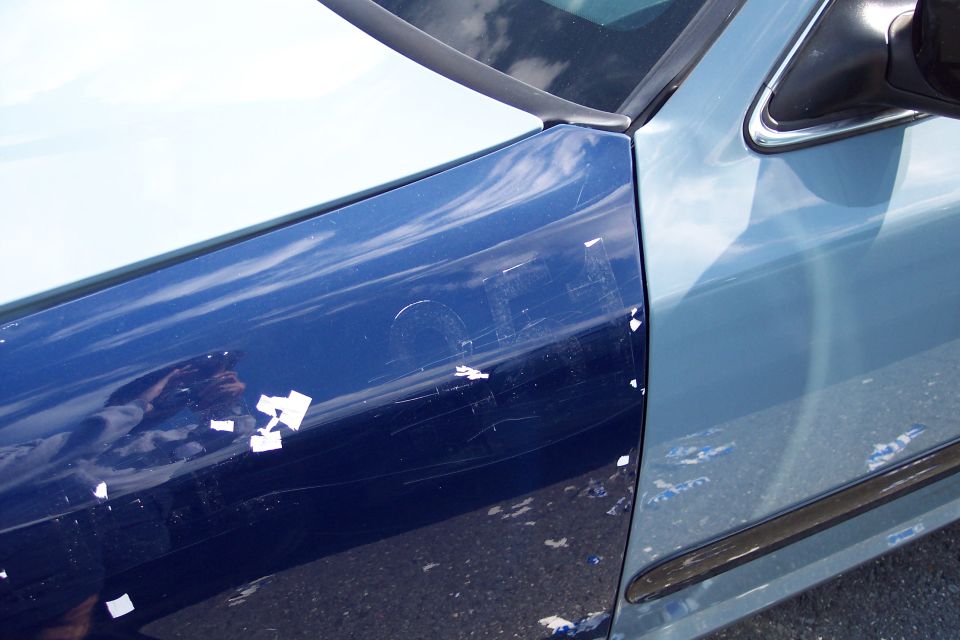 Blue car door with extensive scratches and peeling paint