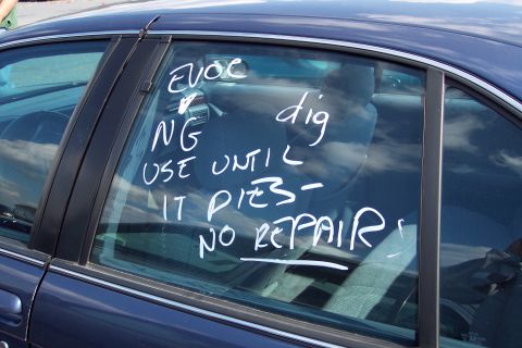 1991 Ford LTD Crown Victoria - White text on the side window of a dark blue sedan reads "USE UNTIL IT DIES - NO REPAIRS".
