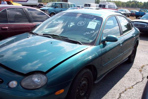 1991 Ford LTD Crown Victoria - A teal sedan is parked in a lot with other vehicles, handwritten markings on its windshield.