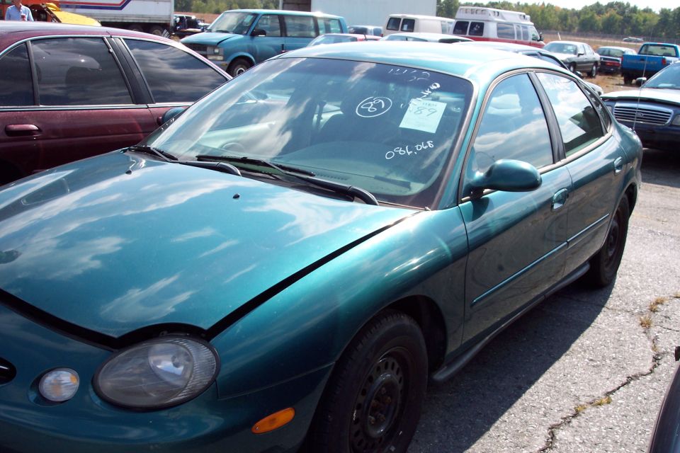Teal sedan, front quarter view, with handwritten numbers on windshield