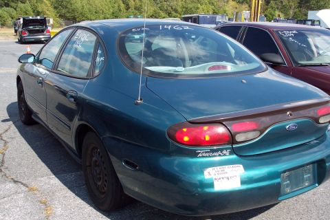 1991 Ford LTD Crown Victoria - A teal Ford Taurus SE is parked in a lot, showing its rear end and a humorous bumper sticker.