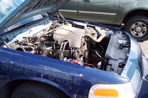 1991 Ford LTD Crown Victoria - Engine bay of a 1991 Ford Crown Victoria LTD, with a green SUV in the background.