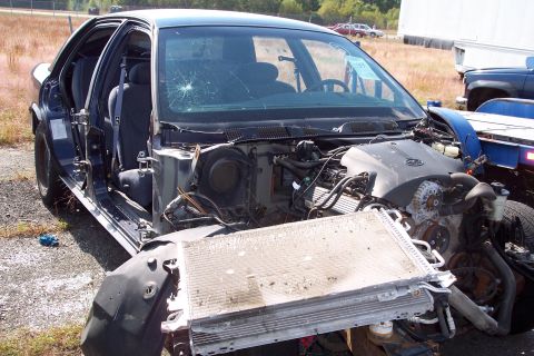 1991 Ford LTD Crown Victoria - This sedan has sustained significant front-end damage, exposing its engine and cooling system.