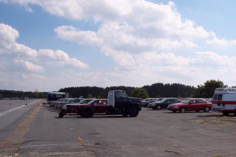 1991 Ford LTD Crown Victoria - A custom vehicle combines a truck chassis with a red car body, parked in a lot with other vehicles.