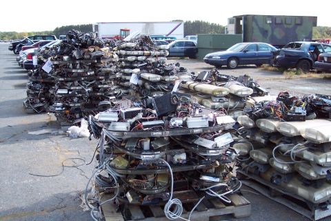 1991 Ford LTD Crown Victoria - Stacks of discarded police light bars are piled on pallets, showing their internal wiring and electronic components.