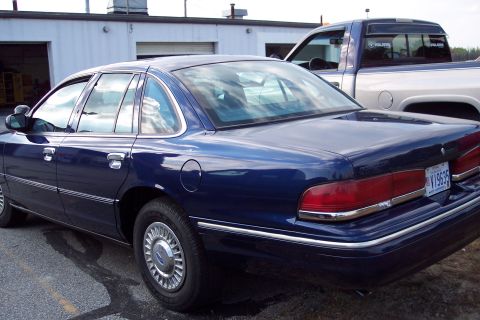 1991 Ford LTD Crown Victoria - Rear view of a blue sedan, parked next to a pickup truck.