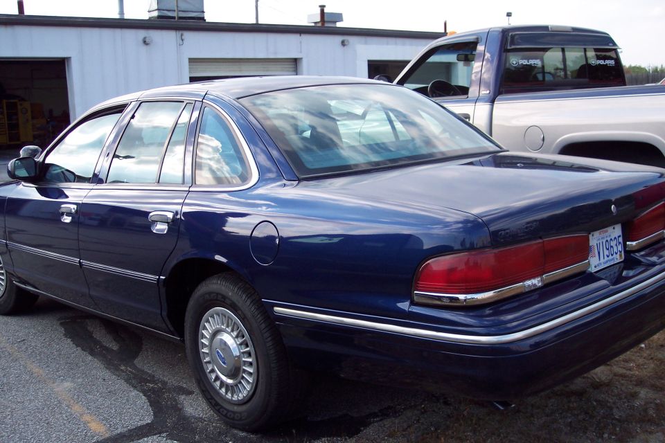 Blue sedan parked next to a pickup truck. License plate reads V19635