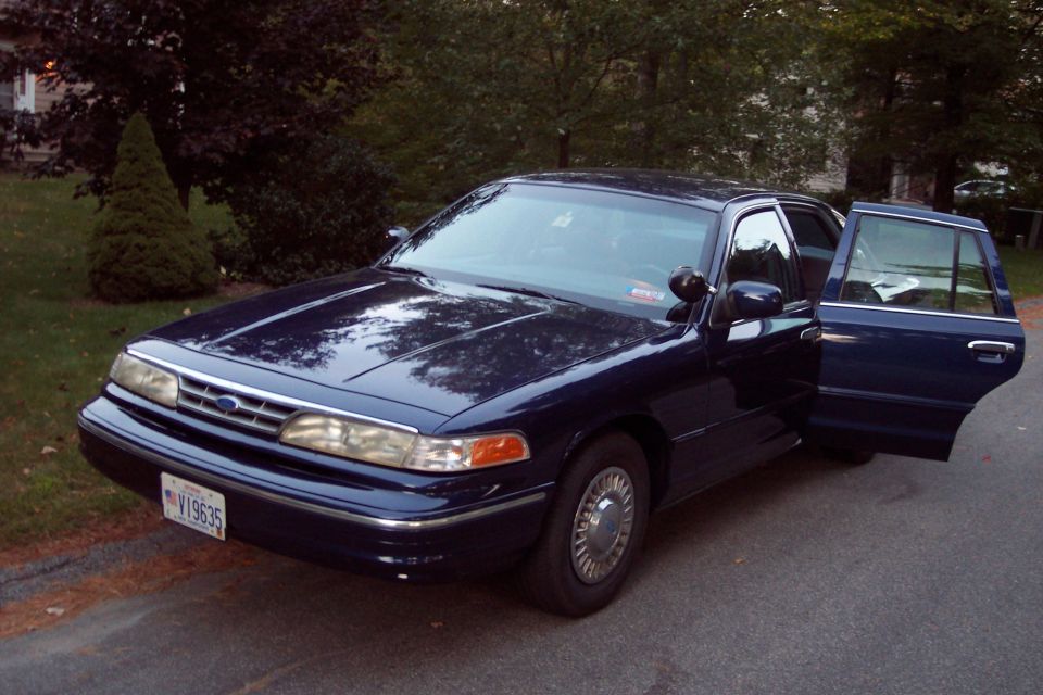 Dark blue sedan with front passenger door and rear driver's side door open, parked on asphalt