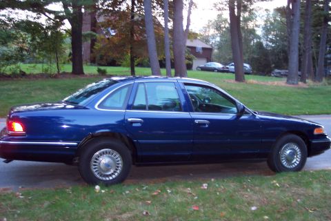 1991 Ford LTD Crown Victoria - Side profile of a blue 1991 Ford Crown Victoria LTD sedan parked on a grassy area.