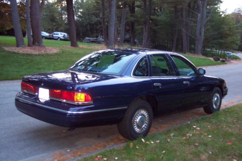 1991 Ford LTD Crown Victoria - A dark blue sedan is parked on the side of a road with trees in the background. The vehicle appears to be a 1992 model.