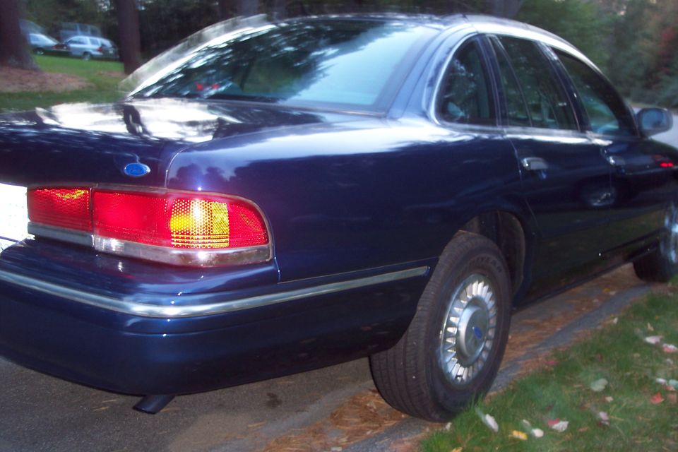 Dark blue 1991 Ford Crown Victoria LTD rear quarter view. Chrome trim and distinctive taillights visible