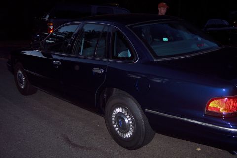 1991 Ford LTD Crown Victoria - A dark blue sedan is parked on a street at night, with another vehicle visible in the background.