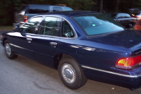1991 Ford LTD Crown Victoria - A dark blue 1991 Ford Crown Victoria LTD sedan is parked on a paved surface, with other vehicles visible in the background.