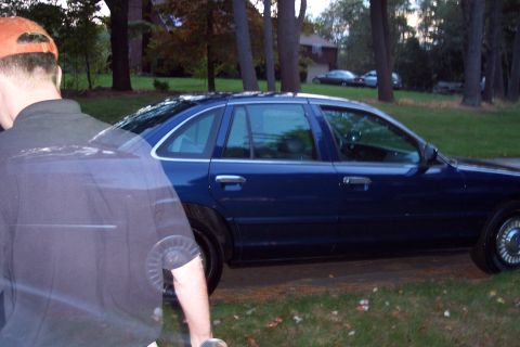 1991 Ford LTD Crown Victoria - A blue sedan is parked on a grassy area with trees in the background.