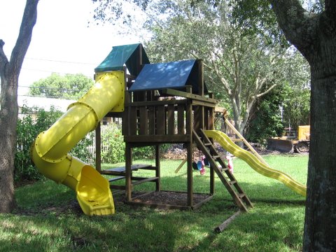 1993 Ford C-350 (Centurion Conversions) - Backyard playset with yellow slides and a wooden fort structure.