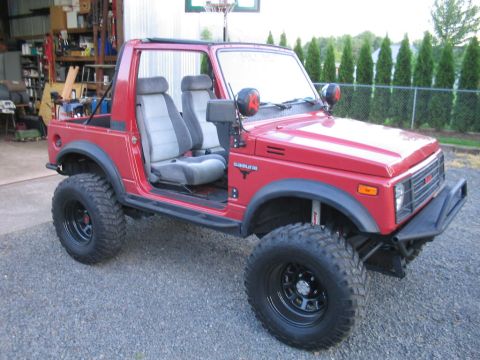 1987 Suzuki Samurai - Modified 1987 Suzuki Samurai parked in a driveway with a garage in the background.