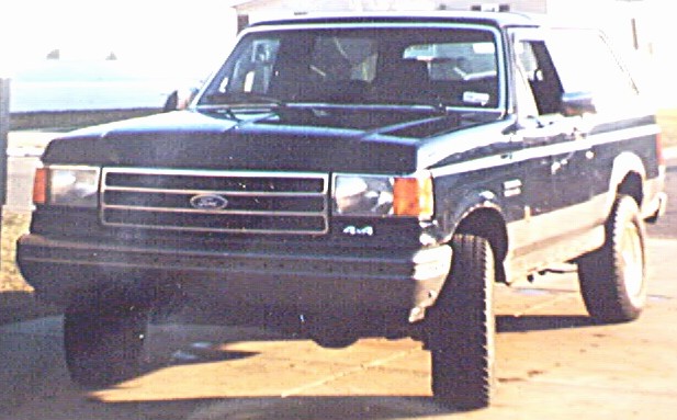 Black late-1980s Ford 4x4 with white roof, front three-quarter view on dirt