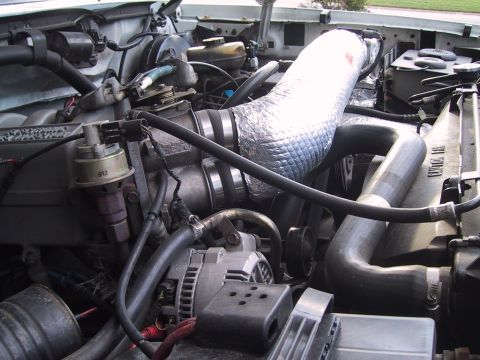 1994 Ford Bronco - Close-up view of a vehicle's engine bay, focusing on the intake system and alternator.