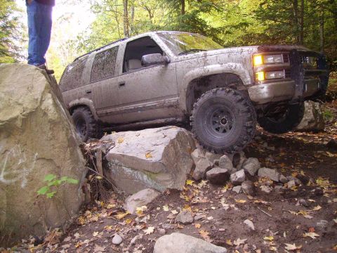2000 Chevrolet Tahoe - This SUV is shown off-roading over large rocks, with its front right wheel significantly elevated.