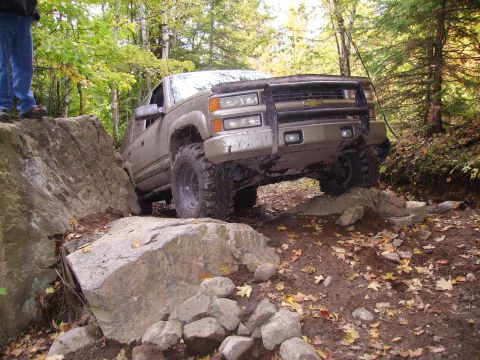 2000 Chevrolet Tahoe - A silver SUV navigates a rocky trail, demonstrating its off-road capabilities.