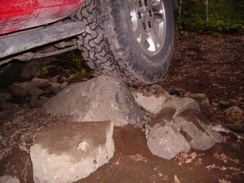 2000 Chevrolet Tahoe - A red SUV navigates a rocky trail, demonstrating its off-road capability.