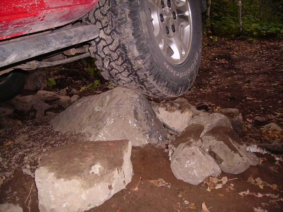 Red SUV tire on rocks, off-roading