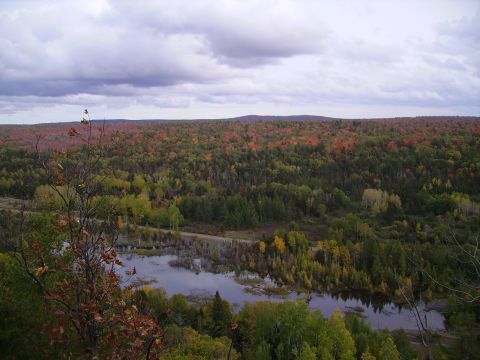 2000 Chevrolet Tahoe - A scenic view of a lake surrounded by trees displaying fall foliage under a cloudy sky.