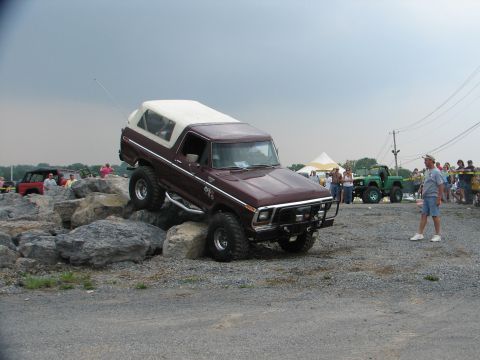 1992 Ford Bronco - Maroon Ford Bronco navigates a rocky obstacle course with a green Jeep visible behind it.